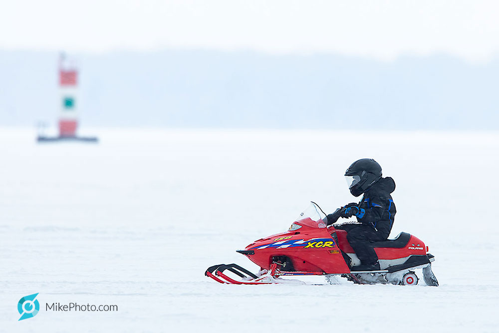 Child on snowmobile passing, in approx. 34 feet water depth with daymark in the background