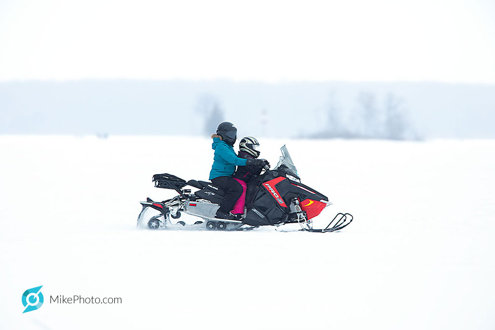 Mom with child, snowmobiling at good speed on Georgian Bay